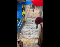 Flood water gush down subway station stairs