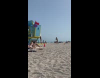 Girl poses with lifeguard tower for photo