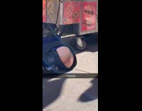 Man sleeps on the ground in front of hot dog cart with pants down and butt sticking out