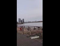 Lady spins around metal pole by river 