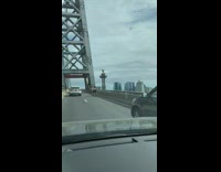Cars pass two girls riding bicycles bridge 