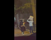 Ladies use storage bin and board as umbrella 