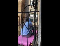 Girl sits pink yoga mat fire escape 