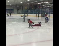 Four kids at skating rink falling on ice with helmets on