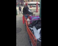 Homeless man pulls shopping carts full of belongings down the sidewalk