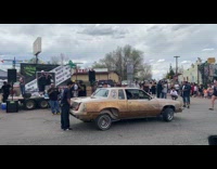 People watch brown car perform hydraulics street