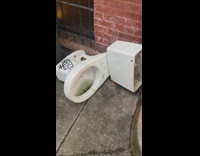 White toilet left on sidewalk black graffiti 