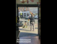 Guy with feathers on head flaps arms like a bird in front of store
