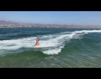 Guy rides on bodyboard pulled by jet ski, rides off dirt ramp and crashes into ocean water