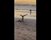 Couple leg split on beach handstand sunset