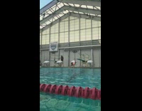 Girl jumps off diving board in indoor swimming pool and belly flops