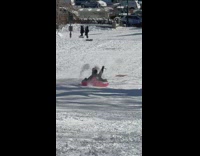 Guy sledding on snow with inflatable tube at park