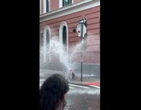 Man sitting by fire hydrant with water bursting out