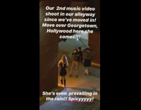 Woman black dress music video shoot parking lot raining