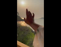 Woman touches sun over water 