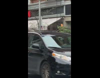 Guy in blue hoodie practices boxing punch and fights with light post on the sidewalk
