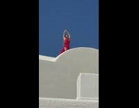 Woman in red dress raise both hands pose in Santorini