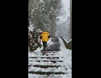 Guy in yellow jacket walks up stairs in snow