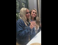 Two girls pose with drinks denim jacket