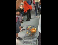 Guy peels a carrot on blanket on subway train floor