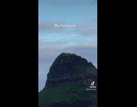 Two girls on the beach while man across on island on rock