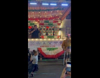 Man sings behind stall while old man dances