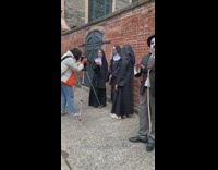 Mime standing next to three nuns on sidewalk 