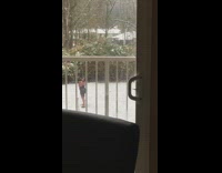 Woman in black dress poses at the snowy backyard with a tripod