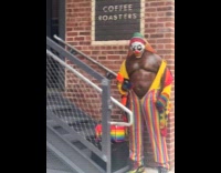 Scary buffed clown wearing rainbow coverall 