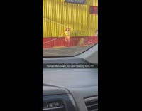 Woman dressed like Ronald Mcdonald poses in front of red yellow building