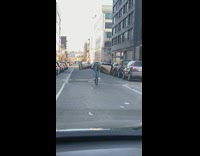 Man Balances Large Carpet Between Arms while on Bike