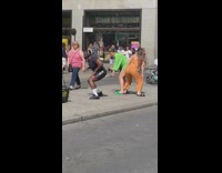 Two women and a man twerks in the middle of the street