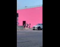 Woman tiktok dances front of pink wall