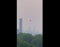 Red sun in middle of smoggy sky 