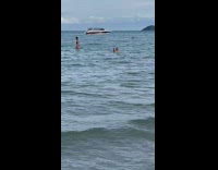 People play volleyball in the beach ocean while man films
