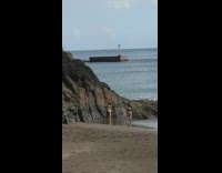 Girl black bikini stand beside rock beach