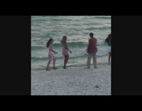 Two girls hold hands jump pose beach 