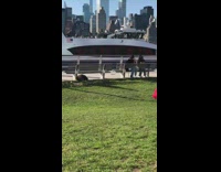 Man Wearing Red Cape Poses While Boat Passes By