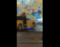 Woman in black dress poses beside the yellow car