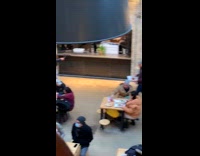 Woman in black trench coat leans on the wall