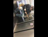 Man carves and saws wood stick pole on subway train