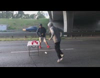 Two guys play beer pong in the middle of a freeway, shoot firecrackers