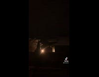 Guy walks up to foot prints in snow and then points at the sky to show a bright blue light 