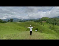 Guy white shirt arms sideward green hill