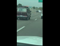Collab Kook Of The Day - Red minivan with loose orange surfboard tied to the roof drives on freeway