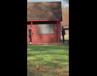 Man in black windbreaker walk and rap near red house