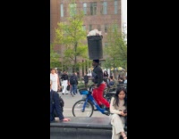 Guy rides bike trash bin on head