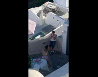 Man in white tank top with sunglasses poses on the balcony