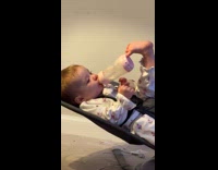 Baby supports milk bottle with its foot