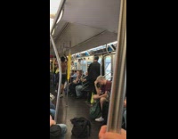 Shirtless guy in black Nike shorts hangs upside down on handrail and spins on poles on the subway